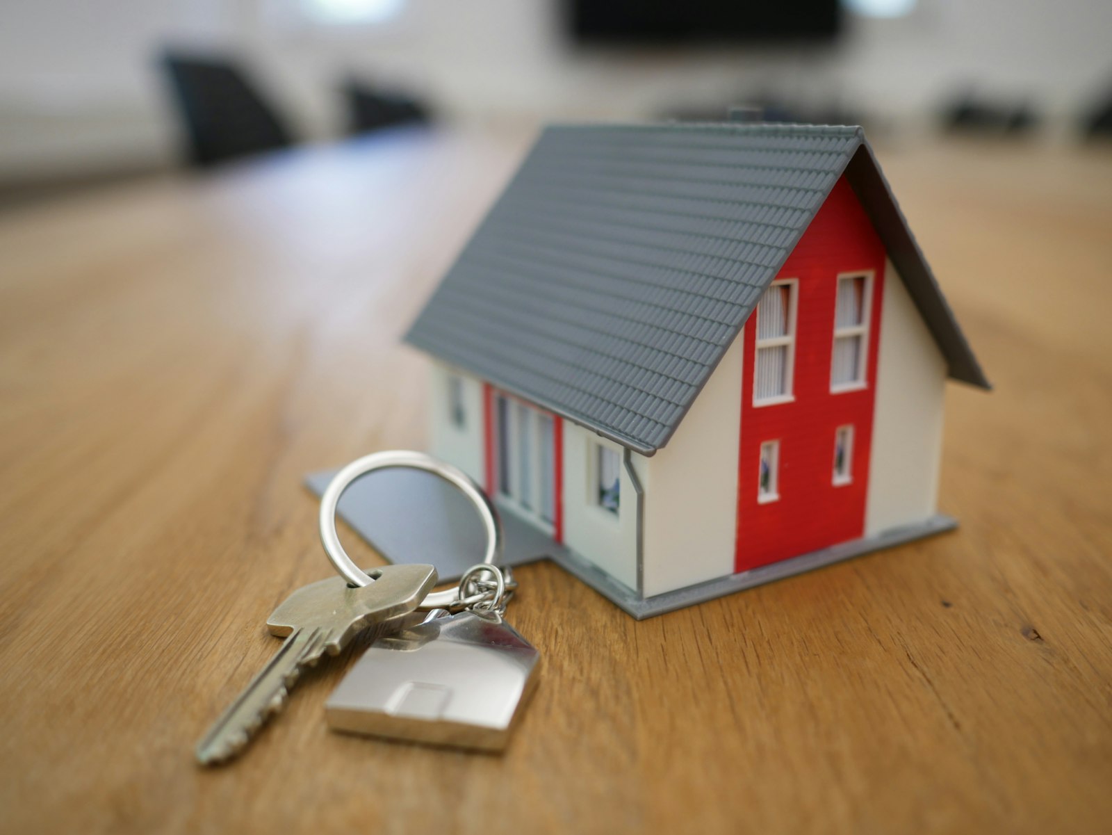 Huissleutels en een miniatuurhuis op een houten tafel — energiecontract regelen bij verhuizen